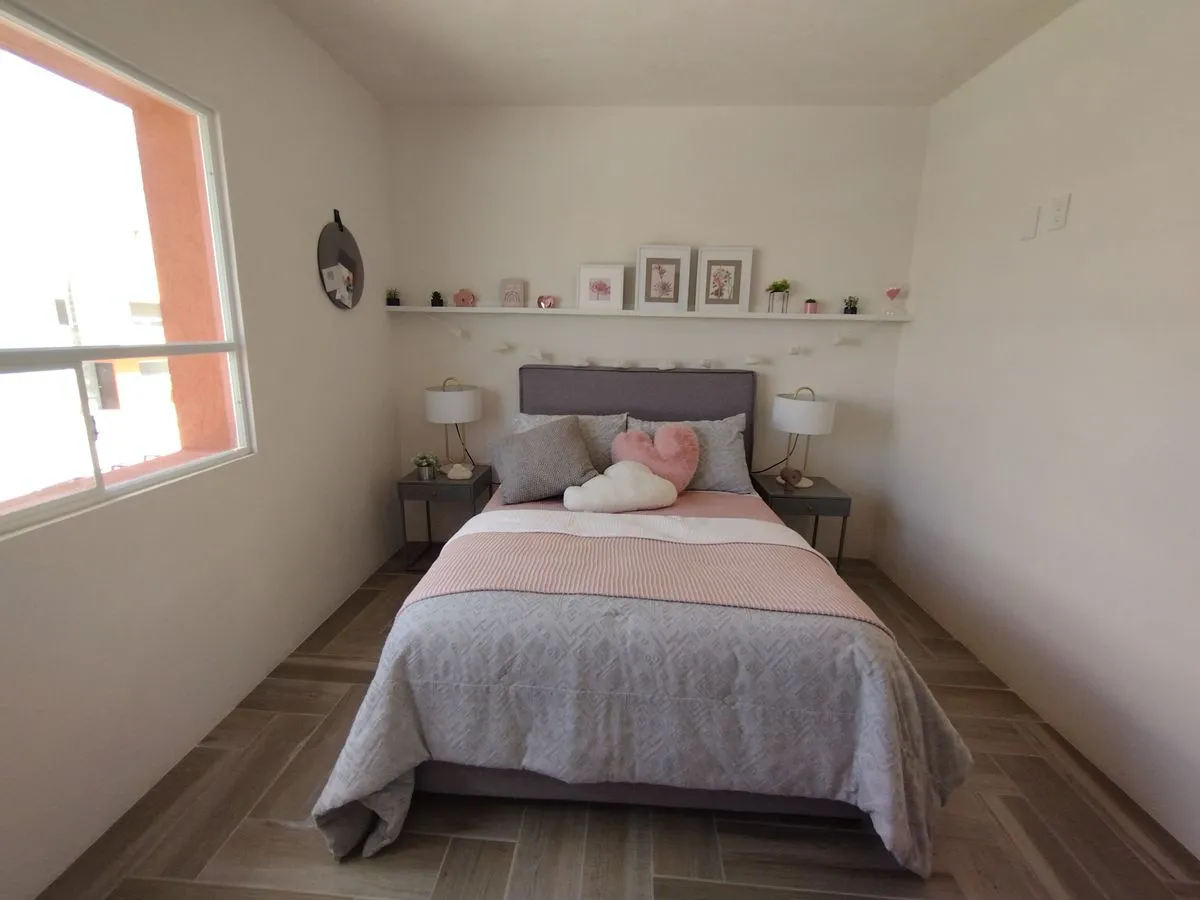 A cozy, minimalist bedroom with soft pink accents and natural light