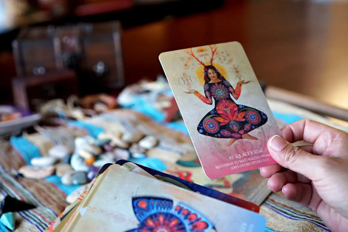 A hand holding a tarot card above a table scattered with stones