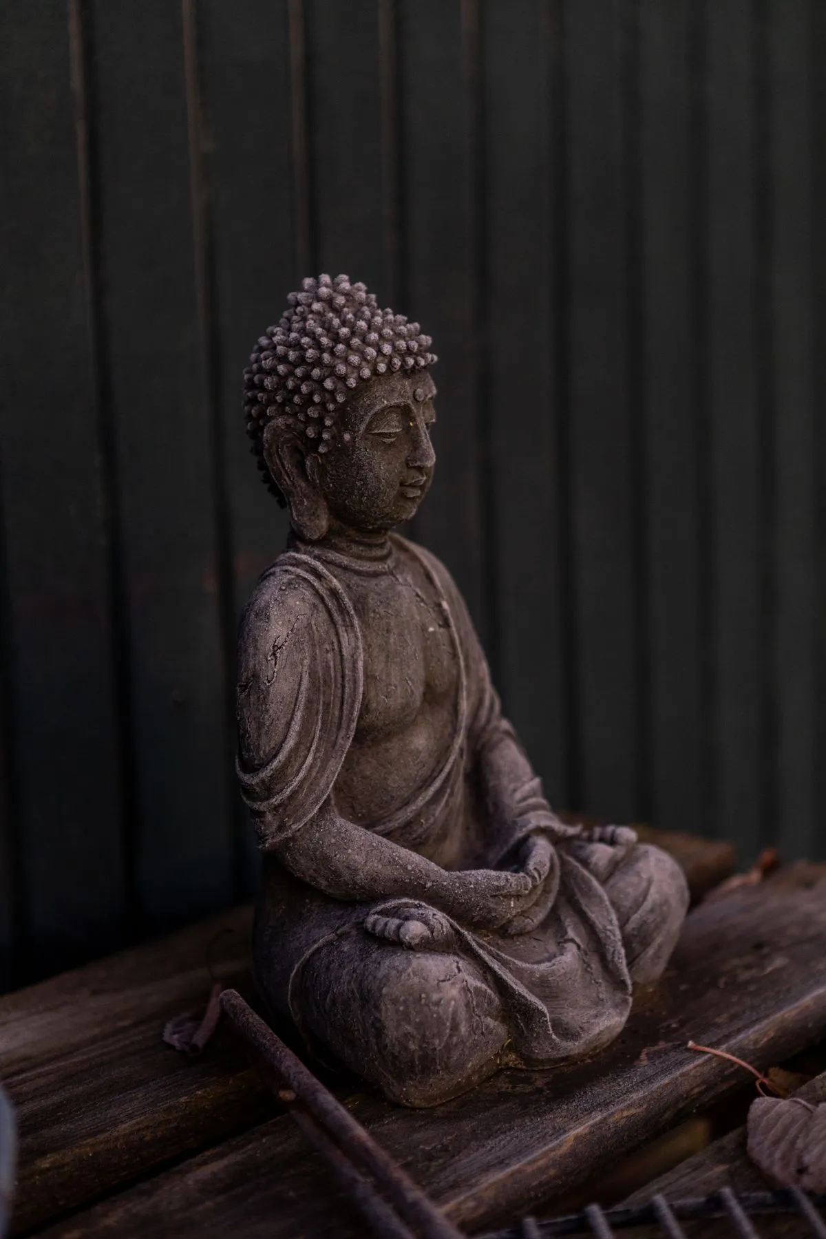 A serene stone Buddha statue in a meditative pose against a dark background